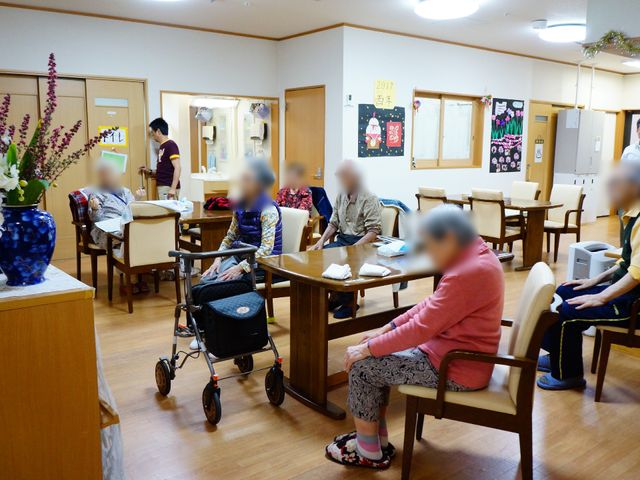 木目調の明るい食堂 リビング5 スタッフが寄り添う温かな食堂で、利用者の方々がお食事や交流を楽しまれています。明るく家庭的な雰囲気が心安らぐ空間です。