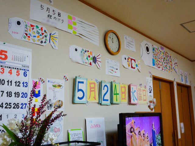 掲示物とテレビのある部屋 掲示板 壁にはカレンダーや手作りの装飾品が飾られ、アットホームな雰囲気を醸し出しています。ここでは利用者の方々が日々の暮らしに彩りを加える工夫がされています。