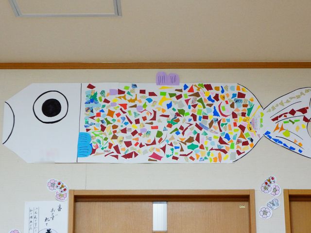 壁に貼られた手作り鯉のぼり 飾られている作品 壁に飾られたカラフルな鯉のぼりが、来る人の目を楽しませています。多彩な活動が期待できる職場です。