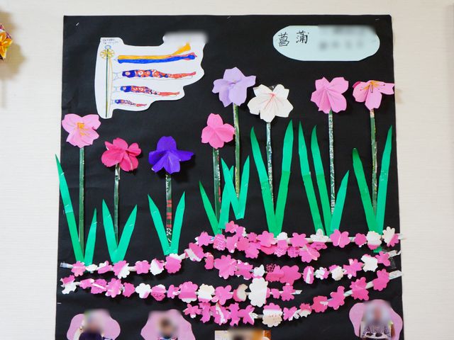 手作りの壁掛けアート 花の飾り 色とりどりの花々が心を和ませる壁面装飾です。創作活動を通じて、利用者の方々の豊かな表現力を感じられる空間が広がっています。