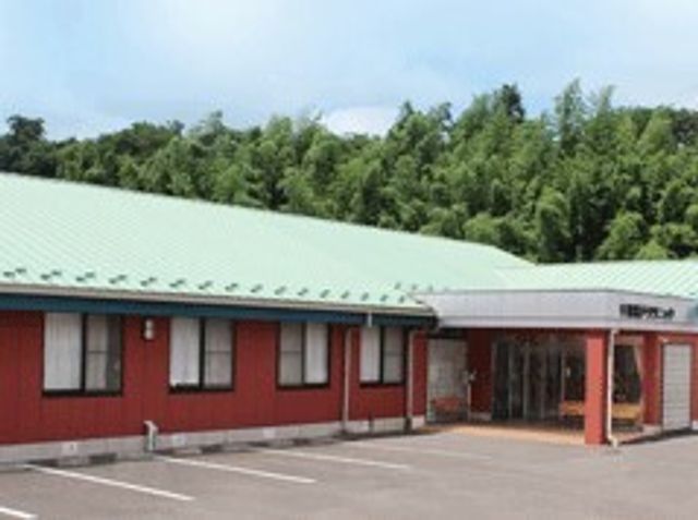 赤い壁の平屋建て施設 千葉横戸クリニック のどかな自然に囲まれた、落ち着いた色合いの建物です。広々とした駐車スペースがあり、アクセスも良好です。