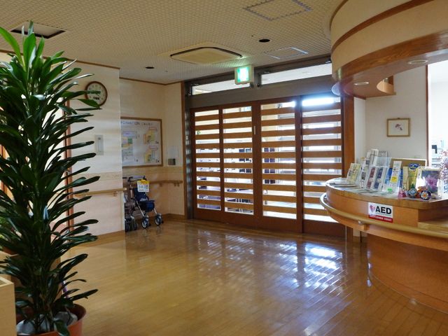 快適なエントランス風景 入り口 明るく開放的な受付スペースです。手すりや車椅子が配慮された空間で、訪れる方々を歓迎しています。