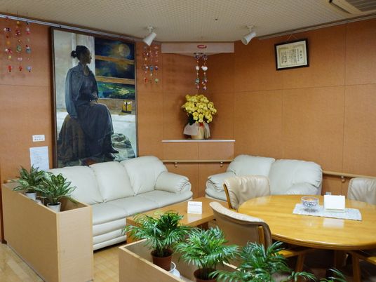 施設には多目的ルームがある。丸テーブルと複数の椅子があり、隣にはソファが設置されている。周りは絵画や花が飾られている。