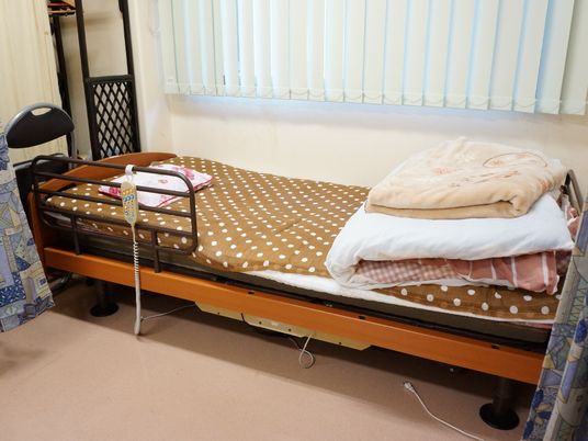 ベッドは電動ベッドを使用。枕元にコントローラがあるため、好みの高さや角度に調節できる。窓にはブラインドがかけてある。
