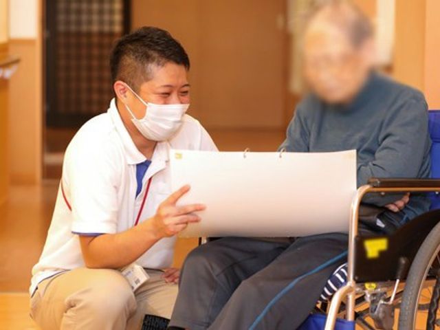 車椅子の利用風景廊下 廊下 スタッフが笑顔で入居者と会話し、親身に接する姿勢が感じられる環境です。