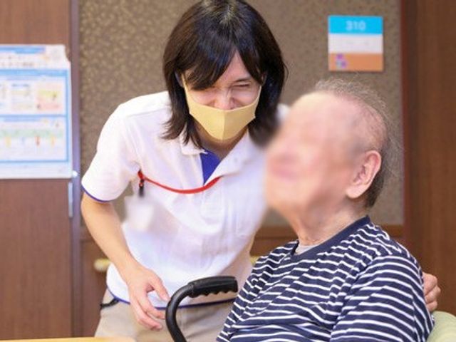 話すスタッフと入居者 スタッフイメージ スタッフが入居者と笑顔で会話をしています。親しい関係が築かれている様子が伺えます。