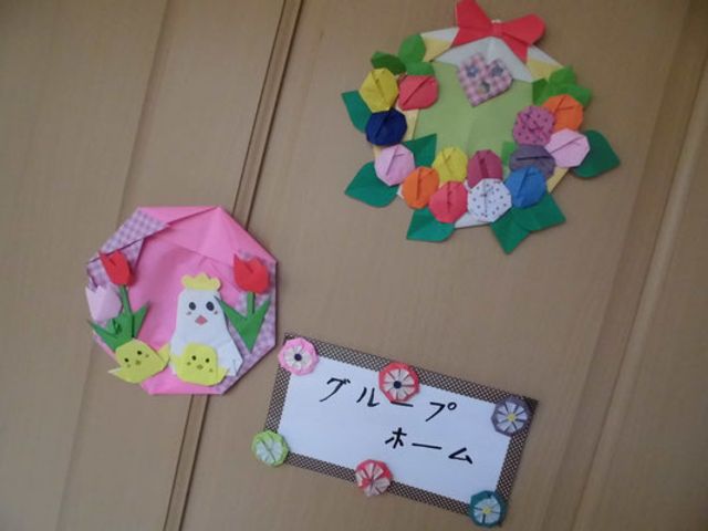 季節の壁飾りと名札 掲示物 壁に飾られた可愛らしい折り紙の装飾。手作り感が溢れるアットホームな雰囲気が参加の楽しさを想像させます。