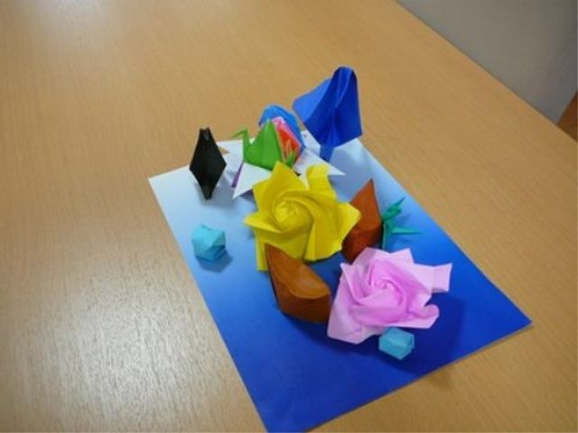 折り紙の花とテーブル 館内環境 丁寧に折られた色とりどりの折り紙は、創造性と細やかな手作業を大切にする環境を示唆しています。
