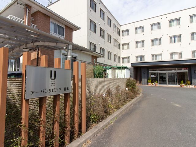 アーバンリビング看板前 外観 清潔感のある外観を持つ建物前に広がる開放的な空間です。明るく落ち着いた雰囲気で、訪れる方を穏やかに迎えます。