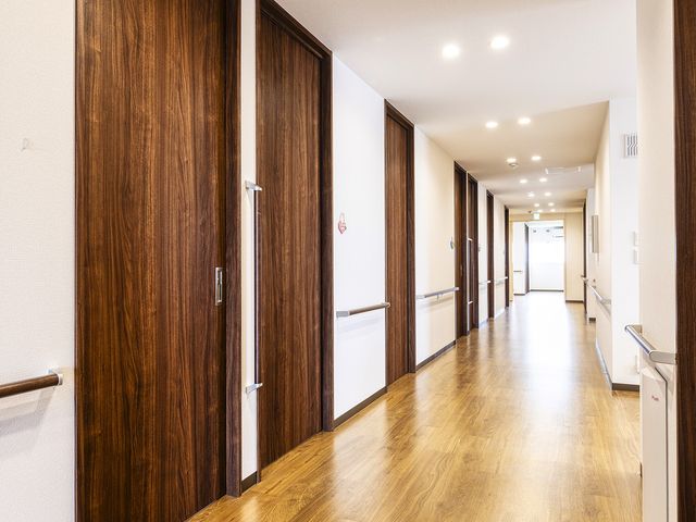 温かみのある廊下 廊下と部屋 手すりが整備された快適な通路です。カラフルな壁飾りが、訪れる人々に心地よい雰囲気を提供しています。