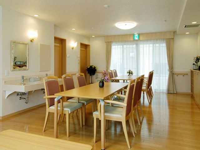 ダイニングの明るい居室 リビング 窓からの光が差し込む清潔なダイニングで、ゆったりとした食事の時間を提供しています。共有スペースでの交流も楽しめる環境を大切にしています。