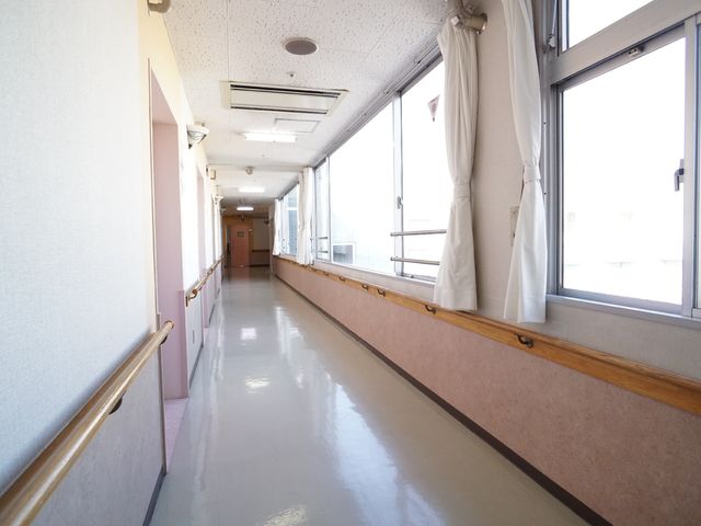 廊下の明るい空間 廊下 窓から日差しが差し込む、清潔感のある通路です。安全を考慮した手すりが設置されています。