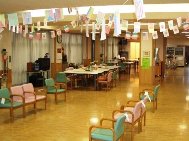 椅子が並ぶリビング リビング 広々とした明るい空間で、椅子に腰掛けながらおしゃべりを楽しめます。上から旗が飾られた楽しい雰囲気です。