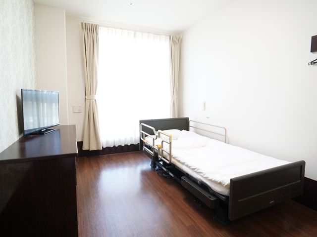 シンプルな個室の居室 居室 床が暖かみのある色合いで落ち着いた雰囲気の居室です。窓からは自然光が差し込み、明るく快適な空間を提供しています。