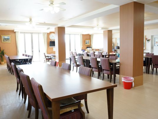 8人掛けのテーブルといすが用意されている、広い食堂。奥には給仕用のカウンターが見える。壁には絵画が飾られ優雅な雰囲気で食事できる。