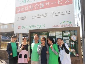 笑顔のスタッフが並ぶ看板前の外観  
