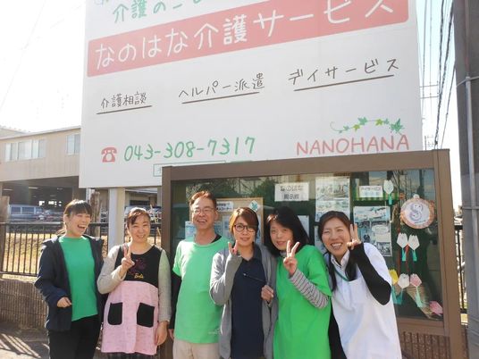 笑顔のスタッフが並ぶ看板前の外観  