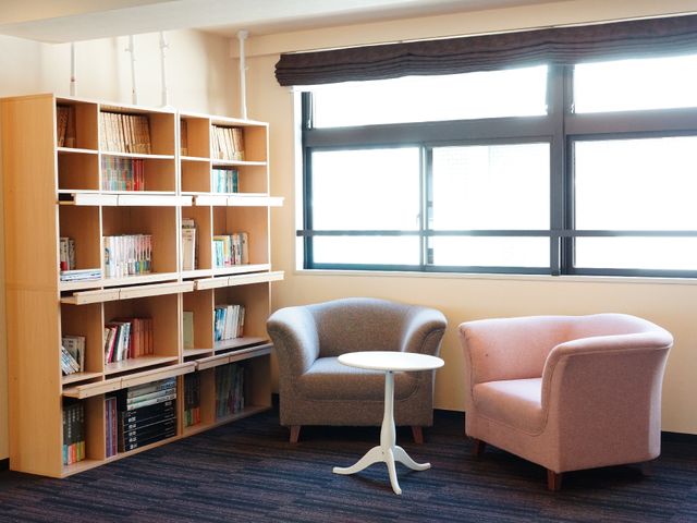 読書スペースの居室 本棚 陽光が差し込む温もりあるラウンジで、ゆったりとお気に入りの本を読む時間をお過ごしいただけます。お一人でも、ご友人とでも、心地よいひとときを。
