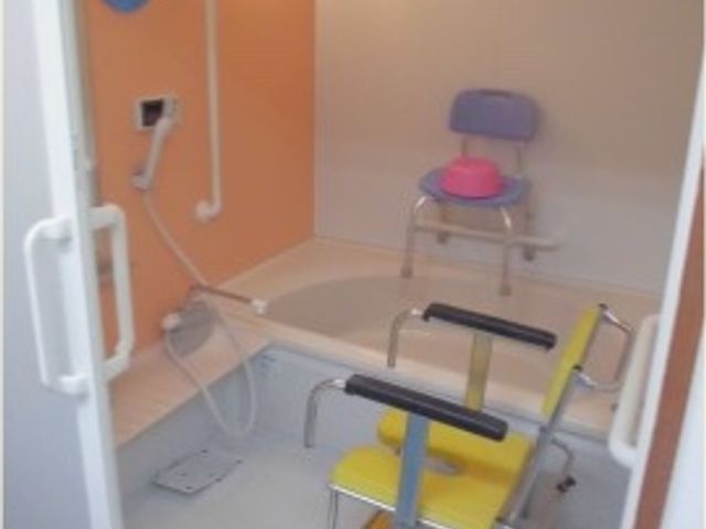 ユニットバスとシャワーチェア 介護浴室 広々とした浴室には手すりやシャワーチェアが完備され、安心してご利用いただけます。身体の不自由な方も快適にお過ごしいただける構造になっています。