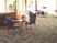 サムネイル レストランのような広々とした空間で、床面はカーペット敷きになっている。木製のテーブルセットが設置されている。