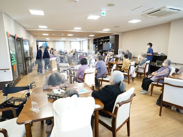 ゆったりとした食堂空間 共有スペース 明るく開放的なスペースで、入居者が食事や憩いの時間を過ごしています。スタッフが笑顔でサポートしており、温かな雰囲気が漂っています。