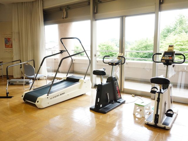 明るい運動設備が並ぶ空間 フィットネスルーム 充実した訓練機器が揃い、日差しの入る開放的な空間で健康を支援します。ご利用者の自立を促進する環境を備えております。