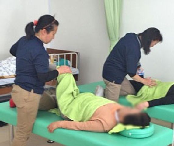 リハビリ中の部屋 機能訓練室 利用者がサポートを受けてリハビリを行っている様子です。必要なサポートが提供されています。