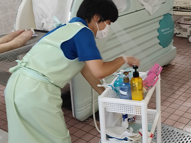 スタッフがケアする浴室 浴室 きれいな空間でスタッフが細やかなケアを行う場面です。快適さが感じられる設計です。