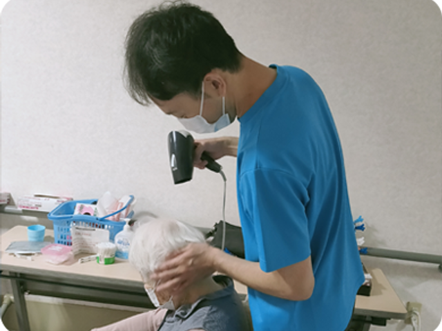 理美容室の様子 理美容室 スタッフが丁寧に髪のケアをしています。利用者との距離が近い温かい雰囲気です。
