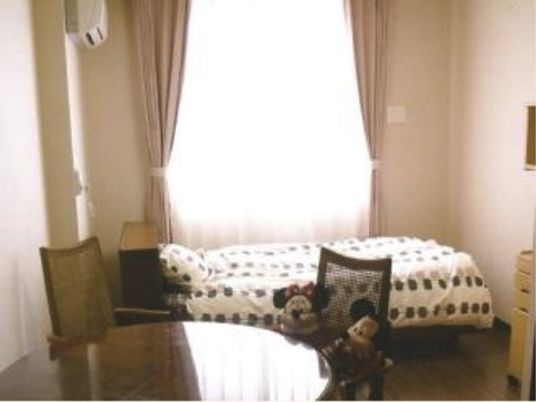 ベッドの横に、大きな丸テーブルと椅子がセットされた寝室