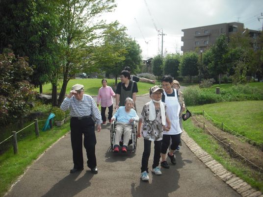 散歩する高齢者とスタッフ