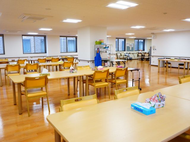 広々した明るい食堂 食堂 広々とした食堂で、テーブルが整然と配置されており、明るい日差しが差し込む快適な空間です。遠くにいる方がリラックスしてお食事をされている様子が見受けられます。