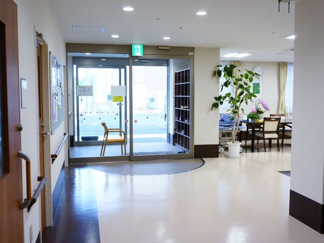 エントランスの開放的空間 玄関前ホール ゆとりのあるエントランスは天井が高く、植物が飾られていて明るい雰囲気です。待合スペースには、快適な椅子が並び、安心して時間を過ごせます。