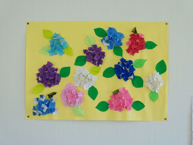カラフルな紙花の掲示物 ちぎり絵 壁に掲げられた手作りの紙花が、日々の活動の一端を伝え、明るい雰囲気を添えています。