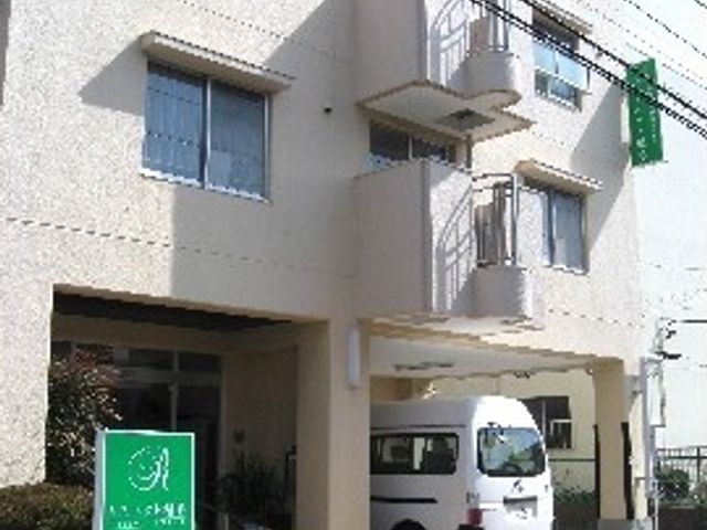 アクセス良好な外観 外観 白基調の建物の入り口前には、送迎車が停まっており、来訪者を温かく迎えています。
