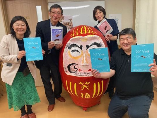 職員が並ぶ掲示物前  