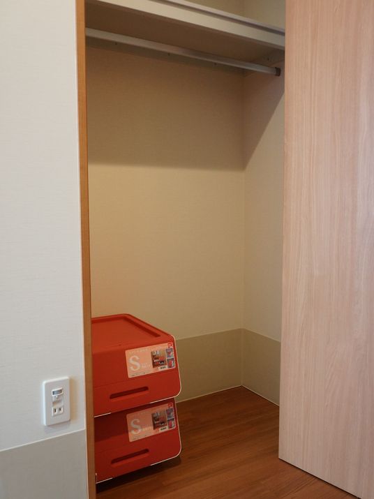 入居者用の個室に用意された収納用スペースの扉を開けたところ。服を掛けられる竿の他、小さな収納ボックスも備え付けられている。