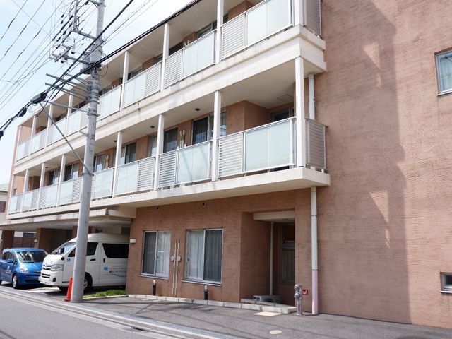 穏やかな雰囲気の建物正面 快適な暮らしの施設 清潔感のある建物外観には、車椅子でも安心して入ることができる広々としたエントランスがあります。この閑静な立地で、心地良い職場環境をご提供しています。