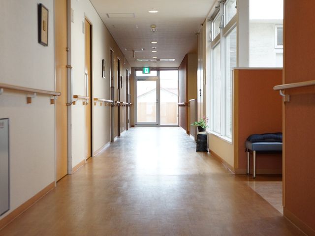 手すり付き明るい廊下 明るく見通しの良い通路 ハンドレールを備えた広々とした廊下です。明るく暖かみのある色合いが心地よい安らぎの空間を提供しています。