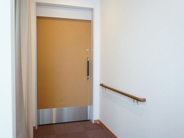 手すり付きの居室入口 ドア 手すりが取り付けられた落ち着いた色合いの入口です。廊下とのスムーズな移動が考えられた設計となっています。