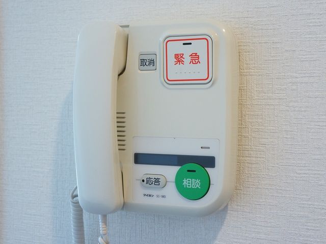 白色のインターホン機器 ナースコール セキュリティがしっかりしたエントランスのインターホンは、安心して暮らせる環境を提供します。緊急時にも迅速に対応できる機能が整っています。