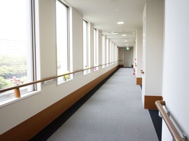 明るい廊下の手すり付き 通路 手すりが設置された清潔感のある廊下は、日差しが入り明るく安全に歩けるようになっています。