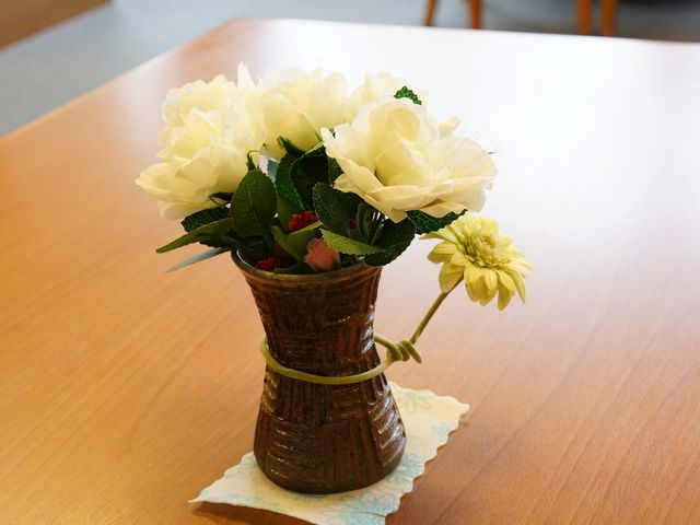 テーブルの花瓶と花 共有スペース 静かな食堂のテーブルには、優しい色合いの花が飾られ、心安らぐ空間が広がっています。