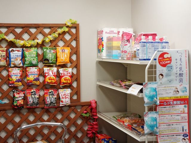 スナック壁掛け陳列 お店 壁面に飾られたスナック類と必需品が、訪れる方々の生活を彩り豊かにしています。利用者の日常が楽しくなる工夫が見えますね。