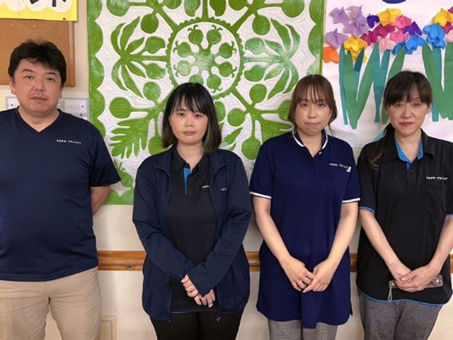 4人のスタッフが並ぶ室内 スタッフイメージ 和やかな雰囲気で、共に働く仲間たちの様子を感じられます。スタッフ間の交流が活発です。