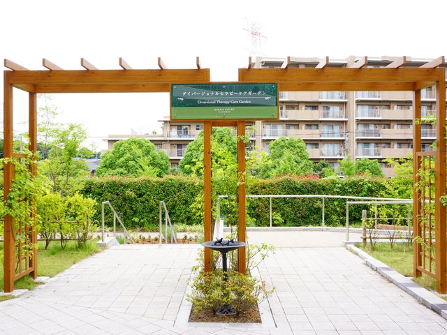 緑あふれる中庭通路 ケアガーデン 木々に囲まれた休息に最適な中庭です。心地よい風を感じながら、穏やかな時間を過ごすことができます。
