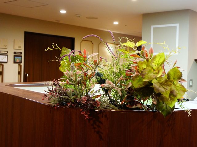 カウンター越しの植物 生け花 ゆったりとした受付カウンターには、心和む植物が飾られており、訪れる人を優しく迎え入れます。
