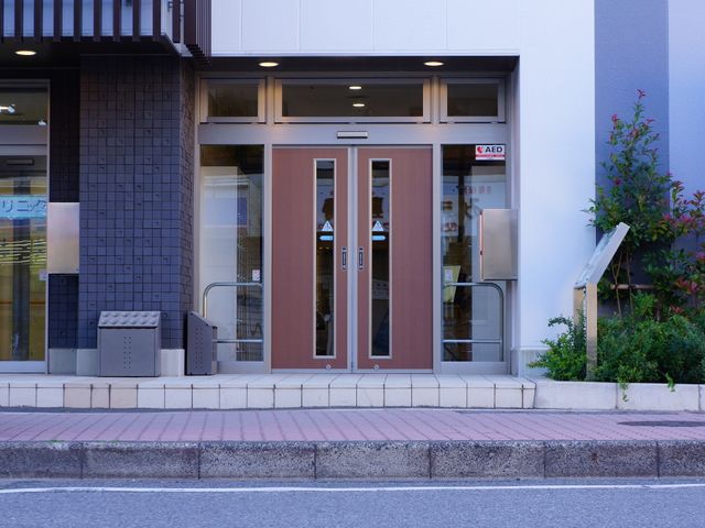モダンな建物の入り口 施設玄関 きれいに整備されたエントランスが皆様をお迎えします。安全面を配慮した、AED設置がある入口です。