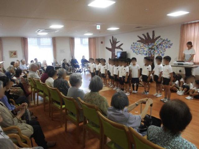 多世代交流のイベント 地域交流 明るい多目的室で、地域の子供たちと笑顔で交流する様子が見られます。心温まるコミュニケーションを大切にしています。