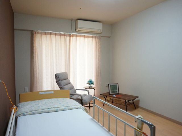 居心地の良い居室 居室 落ち着いた色合いの居室で、快適なリクライニングチェアが備わり、個人の時間をゆったりお過ごしいただけます。明るい窓辺のテーブルは日々の憩いの場となっています。